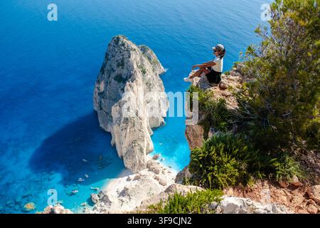 Faszinierende Landschaft von Myzithres in Zakynthos, Griechenland, zeigt azurblaues Wasser und dramatische Klippen. Ein Besucher genießt die ruhige Landschaft, die sein Erlebnis an diesem idyllischen Ort bereichert. Stockfoto