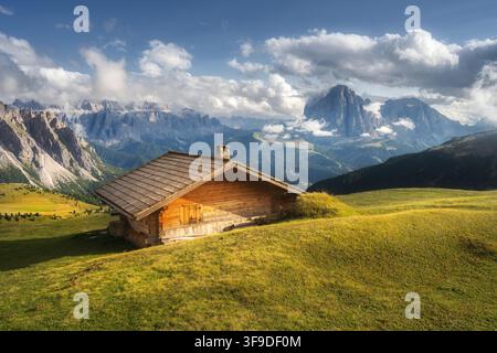 Holzhütte in den Alpen auf einer grünen Wiese auf einem Hügel in den Bergen Stockfoto