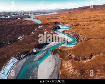 Luftaufnahme des abgelegenen Tals Sary Jaz mit türkisfarbenem, sich windendem Fluss, der durch eine weite, karge Wildnis und eine schroffe Schlucht im Herbst in Kirgisistan fließt Stockfoto