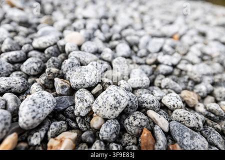 Bett aus Glatten Kieseln und Natursteinen mit hellgrauer Textur, Vollbild-Steinoberflächenhintergrund für Architektur und Design Stockfoto