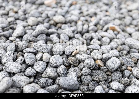 Bett aus Glatten Kieseln und Natursteinen mit hellgrauer Textur, Vollbild-Steinoberflächenhintergrund für Architektur und Design Stockfoto