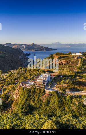 Luftaufnahme einer weißen Villa, die auf einer Klippenküste thront und über das Tyrrhenische Meer sowie die vulkanische Landschaft der Äolischen Inseln in Lipari, Sizilien, blickt Stockfoto