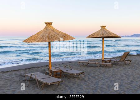 Strohhüte und Sonnenliegen am Tortuga Beach entlang der Adria bei Sonnenaufgang in Ulcinj, Montenegro Stockfoto