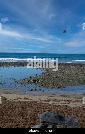 Scenische vertikale Ansicht eines Ufers mit vulkanischen Felsen, algenbedecktem Sand, Horizontlinie und Luftbildrekreation. Stockfoto