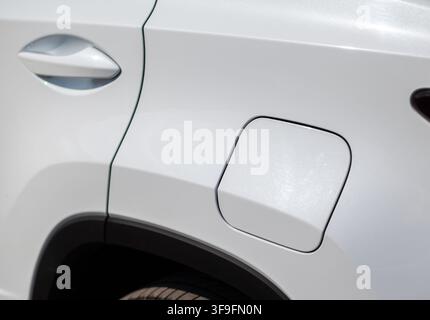 Nahaufnahme der Tankkappe und des Türgriffs eines weißen Autos, die das schlanke Design und moderne Automobilmerkmale präsentieren Stockfoto