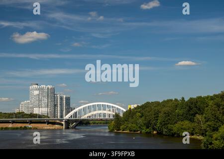 Moskau, Russland – 5. August 2026: Malerischer Blick auf die Khimki-Eisenbahnbrücke, die sich über den Moskauer Kanal spannt, mit modernen Hochhaus-Wohnbauten Stockfoto