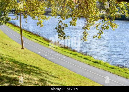 Gemeinsamer Zwei-Wege-Rad- und Fußgängerweg am Ufer eines Flusses an einem sonnigen Herbsttag Stockfoto