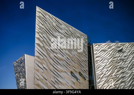 Die kantige Aluminiumfassade des Titanic Belfast erzeugt dramatische geometrische Muster vor einem blauen Himmel im Titanic Quarter. Stockfoto