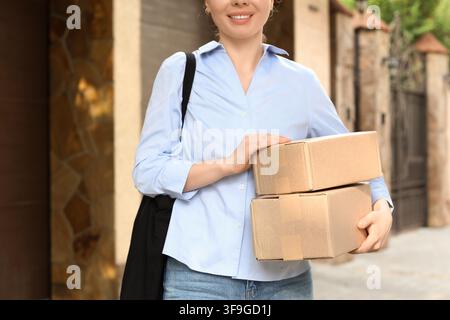 Lächelnde Frau liefert zwei Kartons aus, Paketlieferdienst und Online-Shopping-Konzept, Kurierjob Stockfoto