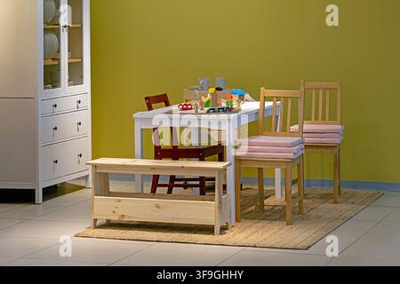 Kindertisch gedeckt mit weißer Tischplatte und Spielzeug auf gewebtem Teppich Stockfoto