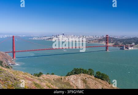 Die Golden Gate Bridge überspannt den Eingang der Bucht, wobei die Skyline von San Francisco von den felsigen Klippen der Marin Headlands aus sichtbar ist. Stockfoto