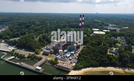 Luftaufnahme des Port Jefferson Kraftwerks mit seinen rot-weißen Schornsteinen, industriellen Strukturen und einem Wandgemälde der amerikanischen Flagge in Port Jeffe Stockfoto