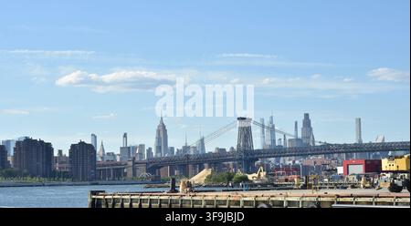 Die Williamsburg Bridge überspannt den East River mit Blick auf die Skyline von Midtown Manhattan, wobei das Empire State Building vom Brooklyn-Ufer aus sichtbar ist. Stockfoto