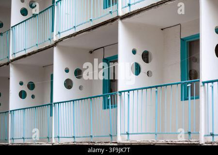 Modernes architektonisches Design einer Gebäudefassade mit kreisförmigen Fenstern und türkisfarbenen Geländern an mehreren Balkonen Stockfoto