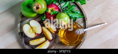 Äpfel, Honig und Granatäpfel auf einem Holzteller zur Vorbereitung auf das jüdische Neujahr Stockfoto