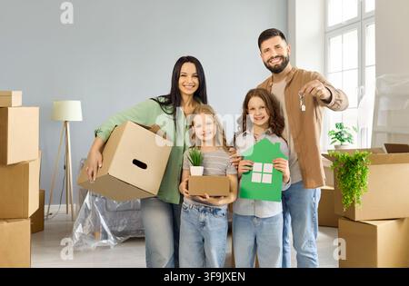 Fröhliche Familie mit Kisten und Schlüsseln zieht in ein neues Haus und feiert gemeinsam Stockfoto