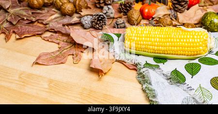 Herbstkomposition mit Mais, getrockneten Blättern, Tannenzapfen, Walnüssen und Kürbissen Stockfoto