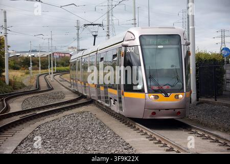 Tallaght, County Dublin, Irland, 15. Aug. 2026 – Das markante weiße Spannzelt, die Inselplattformen, die Oberleitungen, die Richtungsschilder und die Fahrkartenvalidierer am Belgard Luas-Halt der Roten Linie in Dublin. Belgard dient als Kreuzungspunkt für Straßenbahnlinien in Richtung Tallaght und Saggart, mit Fahrten in Richtung Stadtzentrum von Dublin in die entgegengesetzte Richtung. Der Halt wurde für den Saggart-Zweig mit einem zusätzlichen Gleis, veränderten Plattformen und einem das Inselplattformen überspannenden Dach neu konfiguriert, was seine Rolle als Stadtbahn-Interchange im Südwesten Dublins stärkte. Stockfoto