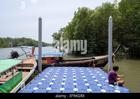 KRABI, THAILAND — 6. MÄRZ 2026: Traditionelle Langschwanzboote liegen an einem schwimmenden Pier neben Mangroven am Krabi-Fluss. Stockfoto