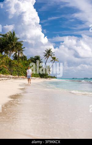 Mann geht entlang eines sandigen tropischen Strandes auf den Malediven Stockfoto