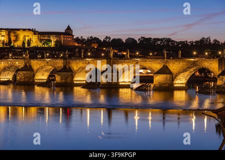 Karlsbrücke an der Moldau bei Einbruch der Dunkelheit in der tschechischen Hauptstadt Prag. Mittelalterliche Steinbogenbrücke abends beleuchtet. Stockfoto
