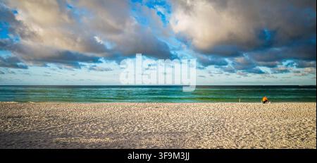 Ruhige frühmorgendliche Aussicht auf einen friedlichen weißen Sandstrand, lebendige blau-grüne Gewässer des Golfs von Mexiko und weiche bewölkte Himmel in Destin, Florida. Stockfoto