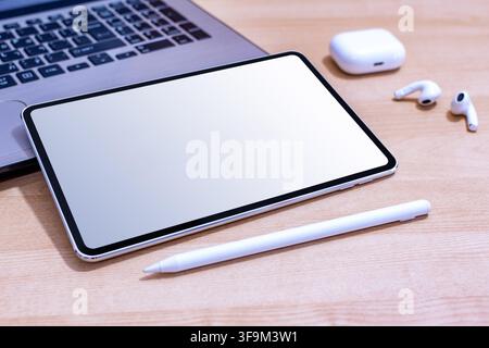 Ein weißes Tablet mit einer schwarzen Tastatur steht auf einem Holztisch. Ein weißer Stift liegt neben dem Tablet Stockfoto