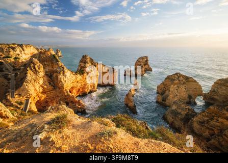 Goldenes Sonnenlicht über der Ponte da Piedade in Lagos, Algarve, Portugal, mit Ozeanklippen, Meeresfelsen, Atlantikwasser und felsiger Küste Stockfoto