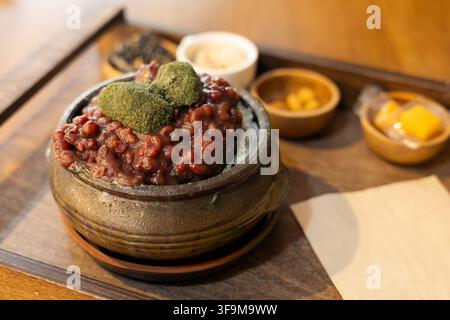 Ein traditionelles koreanisches Eis dessert mit süßen roten Bohnen und grünen Mutterkraut-Reisgebäck oben drauf. Stockfoto