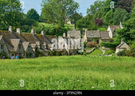 Bibury, England, 03. Juni 2018 - Die ikonischen Steinhäuschen von Arlington Row, gesehen von der anderen Flussseite im malerischen Bibury. Stockfoto