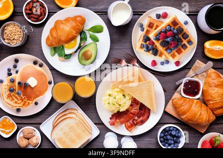Frühstücks- oder Brunch-Tischszene auf dunklem Holzgrund. Blick von oben. Vielzahl an süßen und herzhaften Speisen. Stockfoto