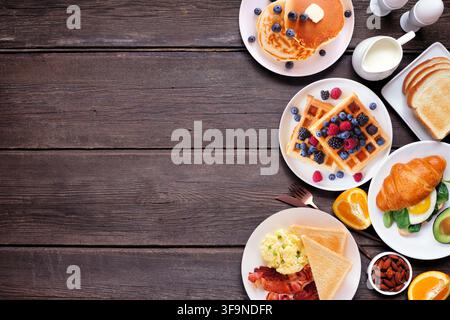 Begleitrand für Frühstück oder Brunch auf dunklem Holzgrund. Blick von oben. Auswahl an süßen und herzhaften Speisen. Stockfoto