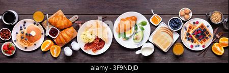 Frühstücks- oder Brunch-Tischszene auf einem dunklen Holzbannerhintergrund. Oberansicht. Sortiment an süßen und herzhaften Lebensmitteln. Stockfoto