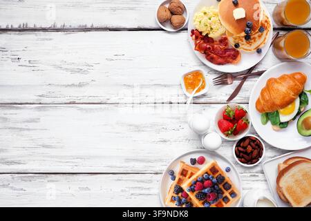 Beilagensborder zum Frühstück oder Brunch auf weißem Holzgrund. Ansicht von oben. Vielzahl an süßen und herzhaften Speisen. Stockfoto