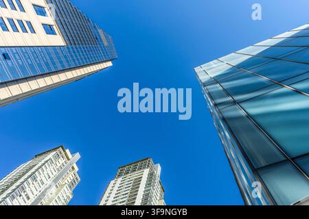 Niedrigwinkelaufnahme von modernen Glasskyscrapern, die sich in den klaren blauen Himmel erheben Stockfoto