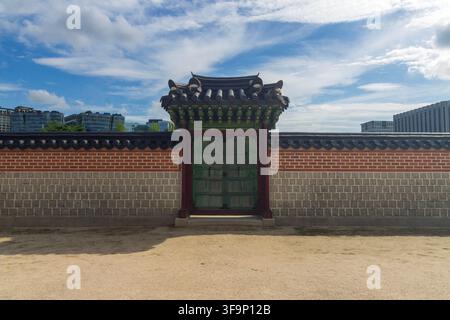 Eine traditionelle gekachelte Wand und ein verziertes Dach stehen vor modernen städtischen Gebäuden unter einem weiten blauen Himmel, der mit geschichteten Wolken gefüllt ist. Stockfoto