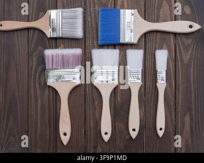 Pinsel auf dunklen Holzbrettern angeordnet für Holzarbeiten, Holzbehandlung, Oberflächenveredelung, Malerei, Renovierung und Möbelrestaurierung Stockfoto