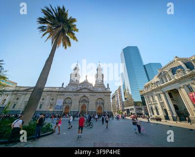 SANTIAGO, CHILE - 03. DEZEMBER 2025: Menschen gehen an der historischen Metropolitankathedrale von Santiago und dem modernen Glaskoloss an der Plaza de Armas vorbei Stockfoto
