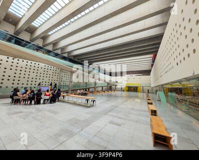 SANTIAGO, CHILE - 03. DEZEMBER 2025: Menschen versammeln sich in der geräumigen unterirdischen Halle des Centro Cultural La Moneda in Santiago, Chile. Stockfoto