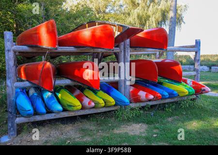 Eine ruhige Szene mit bunten Kanus in einem Rack auf dem Gras Stockfoto