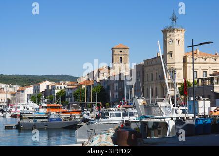 Blick über den alten Hafen von La Ciotat, Frankreich, mit Booten, historischem Rathaus-Uhrturm und Kirchenglockturm an einem sonnigen Tag. Stockfoto