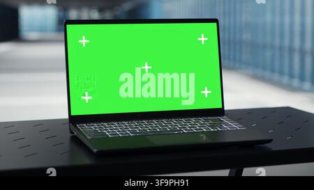 Nahaufnahme eines Green-Screen-Laptops im Rechenzentrum zur Überprüfung der Hardware auf Systemstabilität. Mockup-Notebook zur Überwachung der Serverfarm und zur Konfiguration der Infrastruktur für optimale Leistung Stockfoto