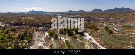 Eine weite erhöhte Ansicht der Li Phi Somphamit-Wasserfälle, die zeigt, wie der Mekong in zahlreiche felsige Kanäle fließt. Stockfoto