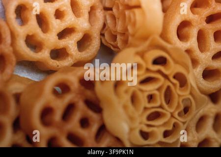 Eine Makroaufnahme mehrerer goldbrauner, knuspriger malaysischer Honigwabenkekse, traditionell bekannt als Kuih Loyang oder Achappam, die eng aneinander gestapelt sind. Stockfoto