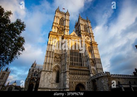 Die historischen gotischen Türme der Westfassade der Westminster Abbey, beleuchtet von warmem goldenem Sonnenlicht unter einer bewölkten Himmel in London, Vereinigtes Königreich. Stockfoto