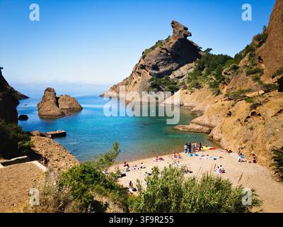 Strandbesucher entspannen sich an der Calanque de Figuerolles in der Nähe der ikonischen Felsformation Bec de l'Aigle in La Ciotat, Provence, Frankreich. Stockfoto