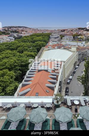 Luftbild einer Dachterrasse mit grünen Sonnenschirmen und Tischen mit Blick auf die historischen Stadtdächer, üppige Bäume und urbanen Straßen von Lissabon, Lisb Stockfoto
