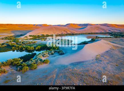 Lebendiges goldenes Sonnenuntergangslicht erhellt die hoch aufragenden Sanddünen im Bruneau Dunes State Park Stockfoto