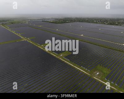 Luftbild einer weitläufigen Solarfarm mit Reihen von Photovoltaikpanelen, die sich unter einem bewölkten Himmel in Miami, Florida, USA, über die Landschaft erstrecken Stockfoto