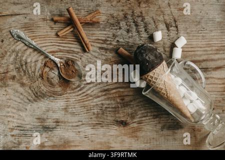 Schokoladeneis in einer Waffel auf einem Holzuntergrund. Süßes Dessert auf dem Tisch. Komposition mit Eiscreme. Süßer Snack. Eis mit Zimt und Stockfoto